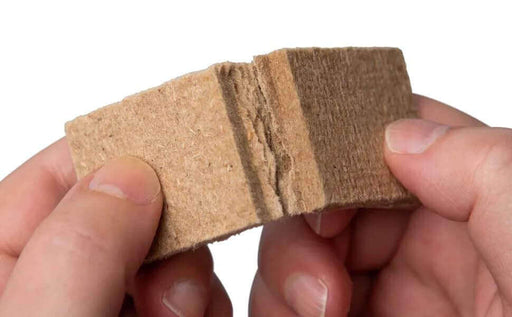 Close-up of hands breaking Imperial TIMBERLITE Firestarter square from Cabin Depot, ideal for fireplaces, grills, and campfires. Safe and easy to use.