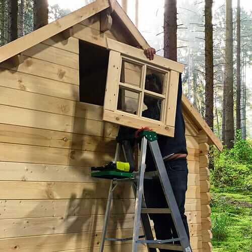 Construction of a Loo Loo House Log Outhouse by Cabin Depot in a forest setting, showcasing versatility as a bus shelter or tiny shed.