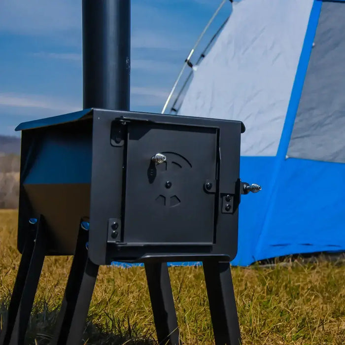 Englander Cub Kit Wood Stove in outdoor setting near blue tent, showcasing welded 12-gauge steel construction and portability.