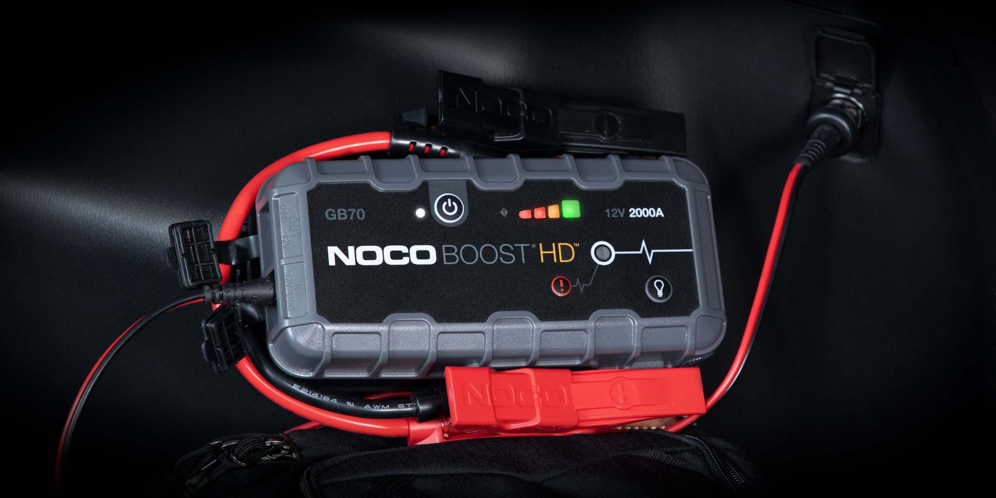 Alt Tag: NOCO 12V 2000A Boost Jump Starter GB70 with cables connected in a car, featuring safety technology, available at Cabin Depot.