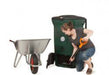 Woman using Biolan 220 ECO Composter with wheelbarrow for efficient year-round composting of kitchen and toilet waste.