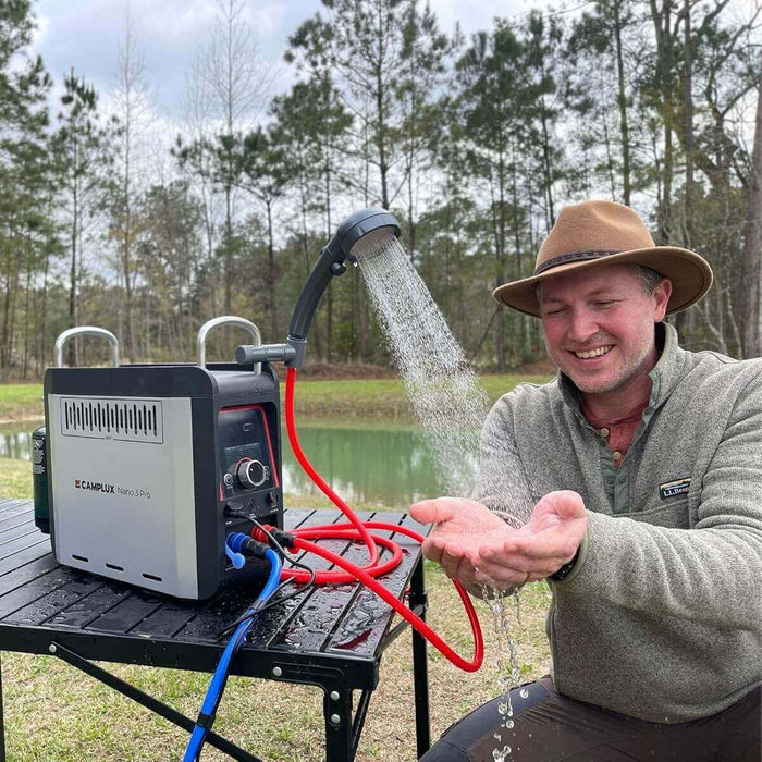 Man using Camplux Nano 3 Pro 12V propane camping shower outdoors, enjoying portable hot water from a table top heater.