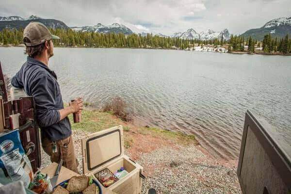 Person enjoying a lakeside view while using a Canyon Coolers 55QT with organizer baskets, available at Cabin Depot.