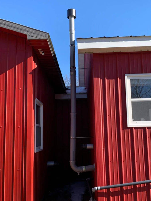 Vertical installation of a Cinderella 4" x 36" flue pipe on a red building, showcasing durable 110mm PP quality.