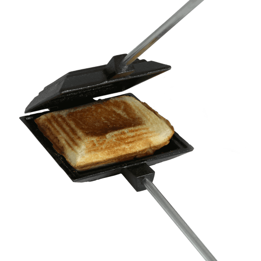 Cast iron camp cooker toasting a sandwich over an open fire, featuring a durable hinge and wooden handles for easy transport.