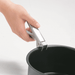 Hand using Coghlans aluminum pot holder to grip a black pot for secure handling.