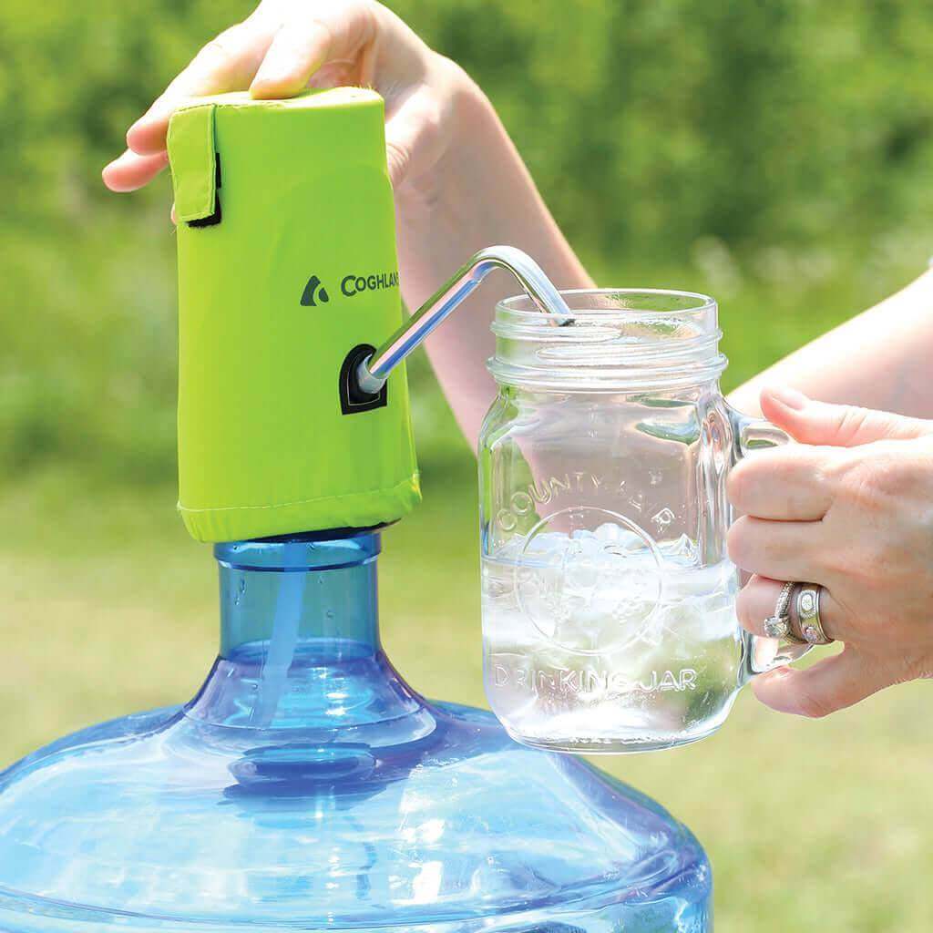Coghlan's Water Pump on cooler jug dispensing water into glass, perfect for Camping with Cabin Depot convenience