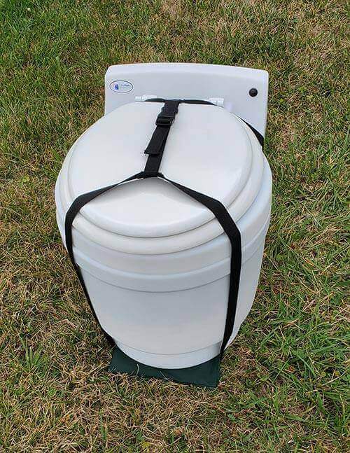 Nylon carrying harness on Laveo Dry Flush Toilet for easy transportation, displayed outdoors on grass.