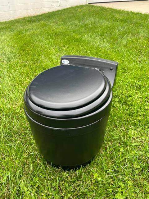 Laveo Dry Flush Portable Toilet on grass, ideal for RV, camping, sprinter, boat, cabin, tiny house - Available at Cabin Depot with free shipping.
