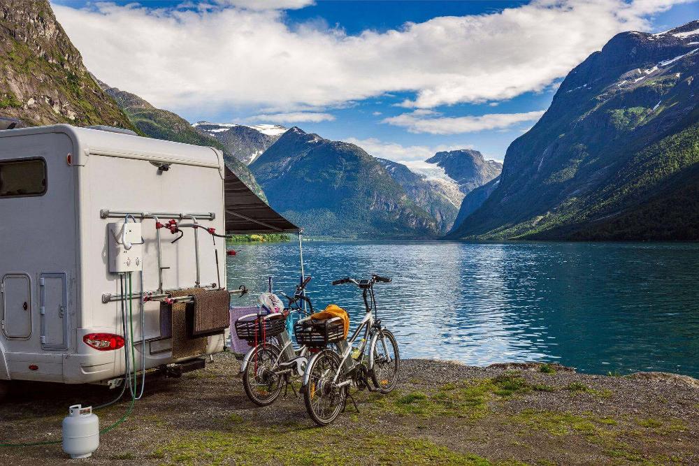Camper van with bikes by a serene lake, showcasing an ideal setting for Eccotemp L5 Portable Tankless Water Heater from Cabin Depot.