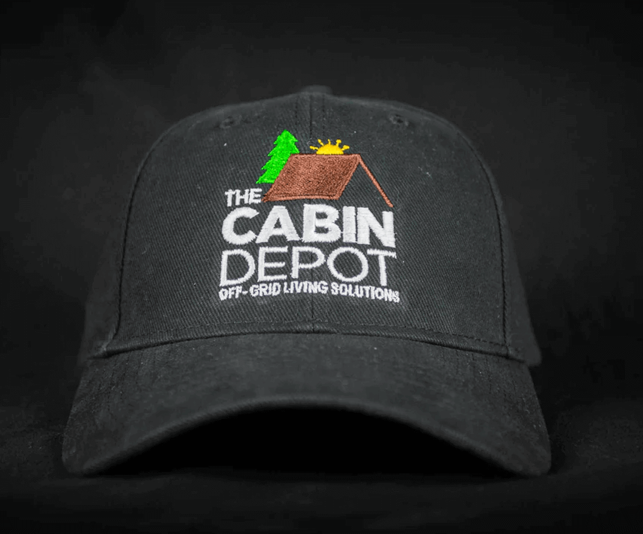 The Cabin Depot logo on black cap, featuring off-grid living solutions design.