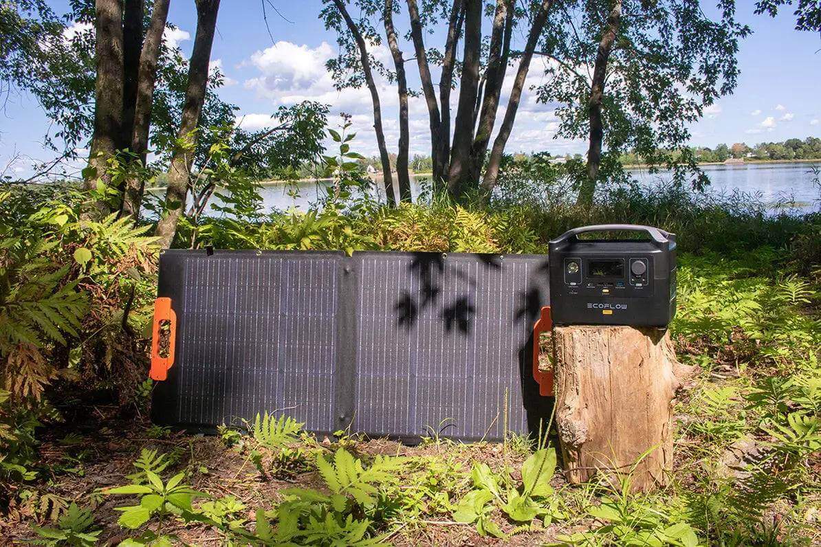 EcoFlow River 2 Portable Power Station with solar panel beside a lake, offered by Cabin Depot for outdoor energy solutions.