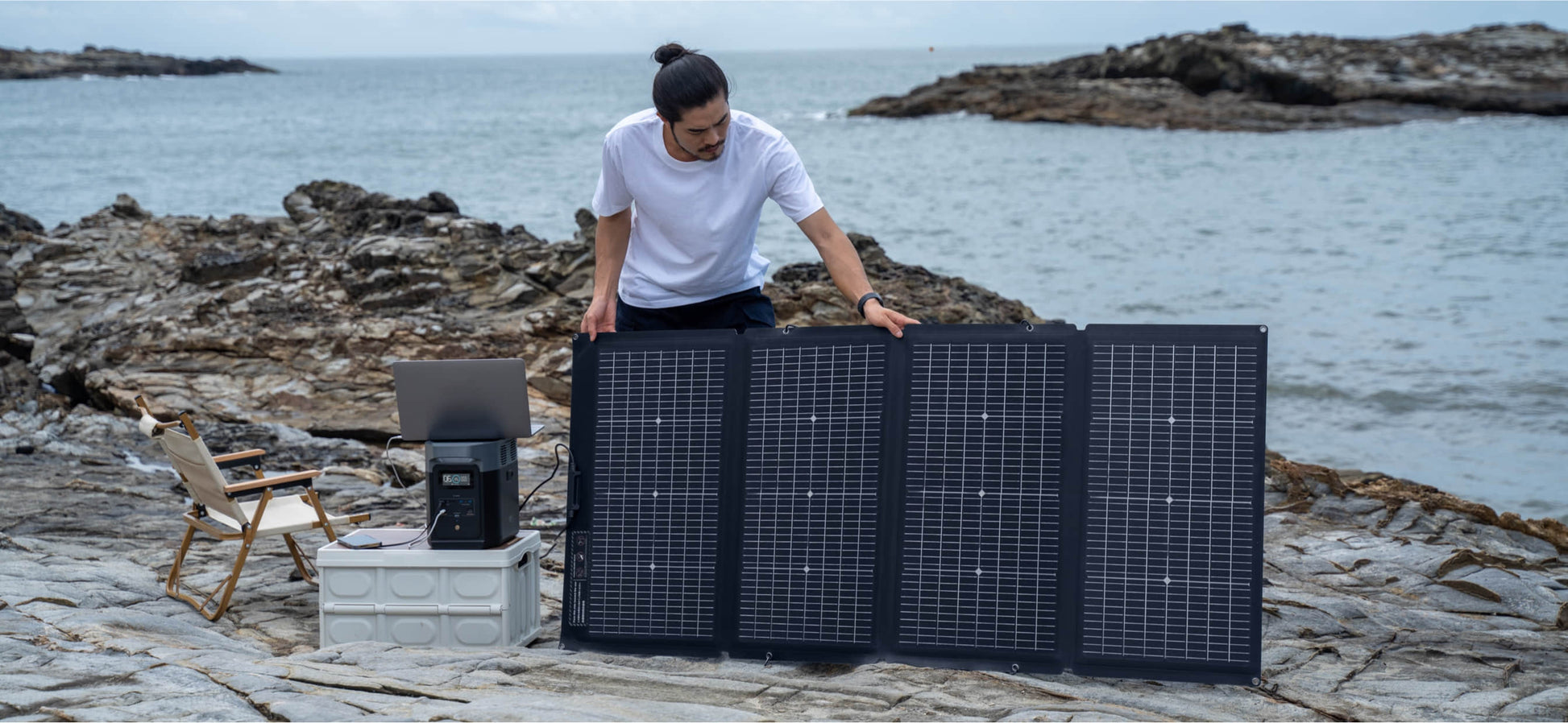 Person using EcoFlow DELTA 2 Portable Power Station with solar panels by a rocky shore, available at Cabin Depot, Canada.