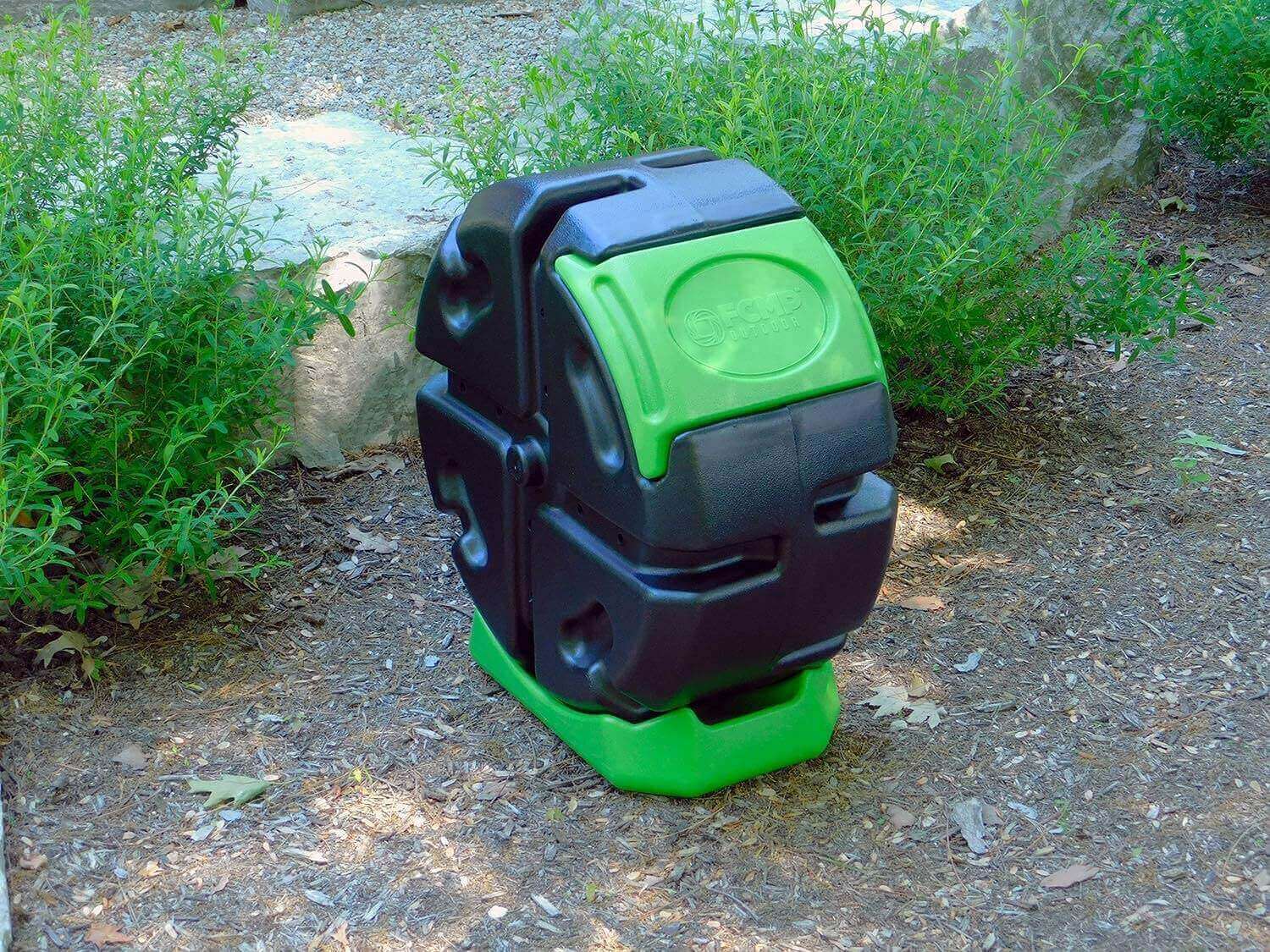 FCMP Outdoor 18.7Gal Rolling Composter in garden, green and black, available at Cabin Depot.