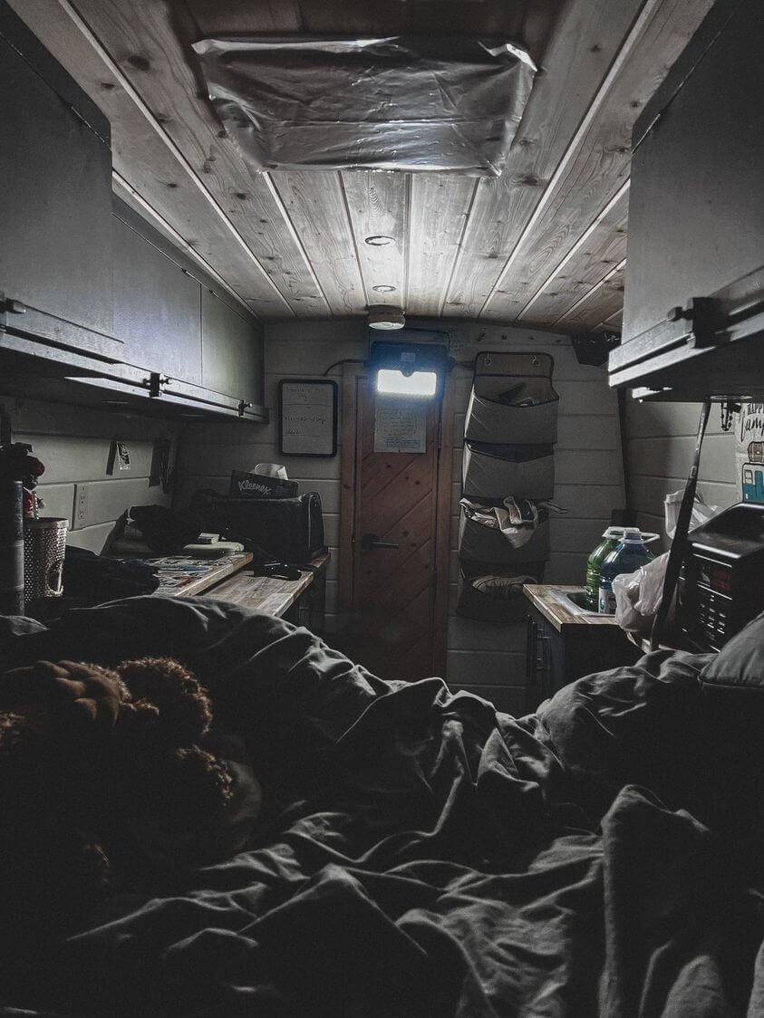 Interior of a cozy cabin with wood ceiling and soft bedding, creating a warm and inviting atmosphere.