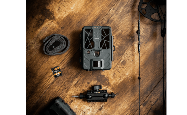 Spypoint FORCE-48 Trail Camera kit with accessories on wooden surface, including memory cards and strap, ideal for high-resolution wildlife monitoring.