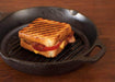 Grilled sandwich with grill marks in Lodge 10.25" cast iron pan, showcasing even heating and seasoned surface.