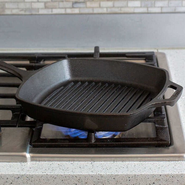 Lodge 10.5" cast iron square grill pan on stove, showcasing grill lines and seasoned surface for home cooking.