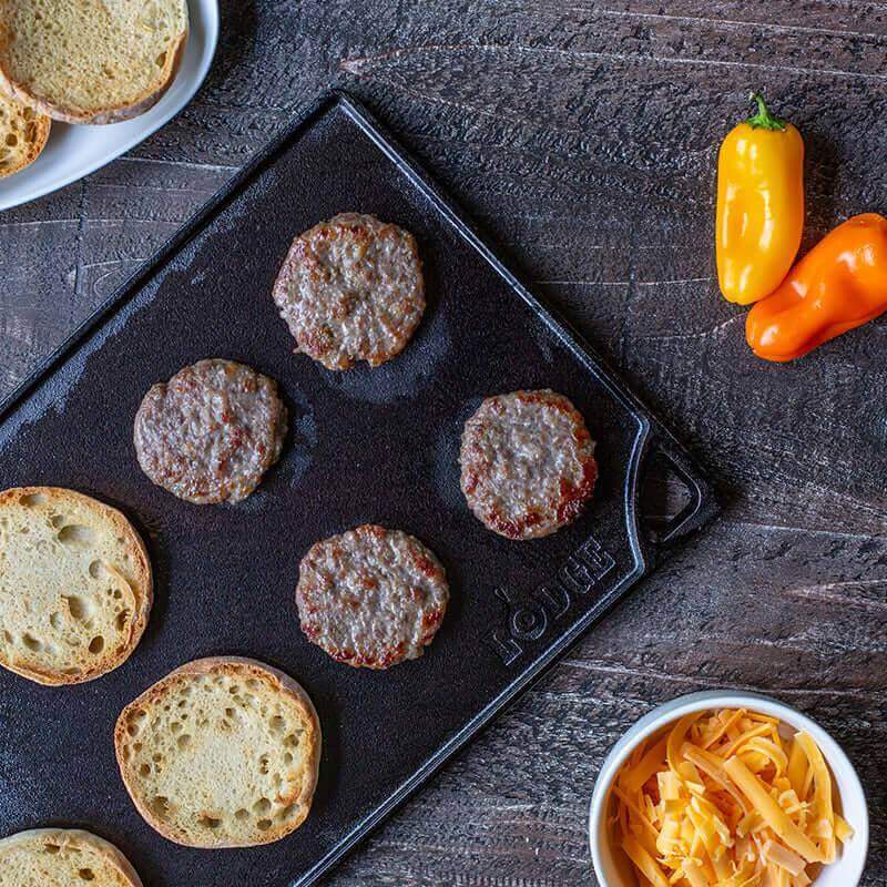 Lodge reversible cast iron grill griddle cooking burgers and buns, available at Cabin Depot.