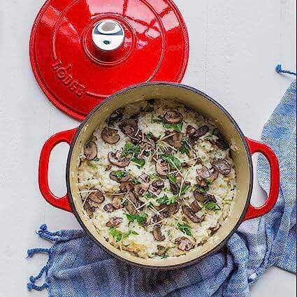 Lodge 5.5 Quart Red Enameled Cast Iron Dutch Oven filled with risotto, featuring mushrooms and herbs, available at Cabin Depot.