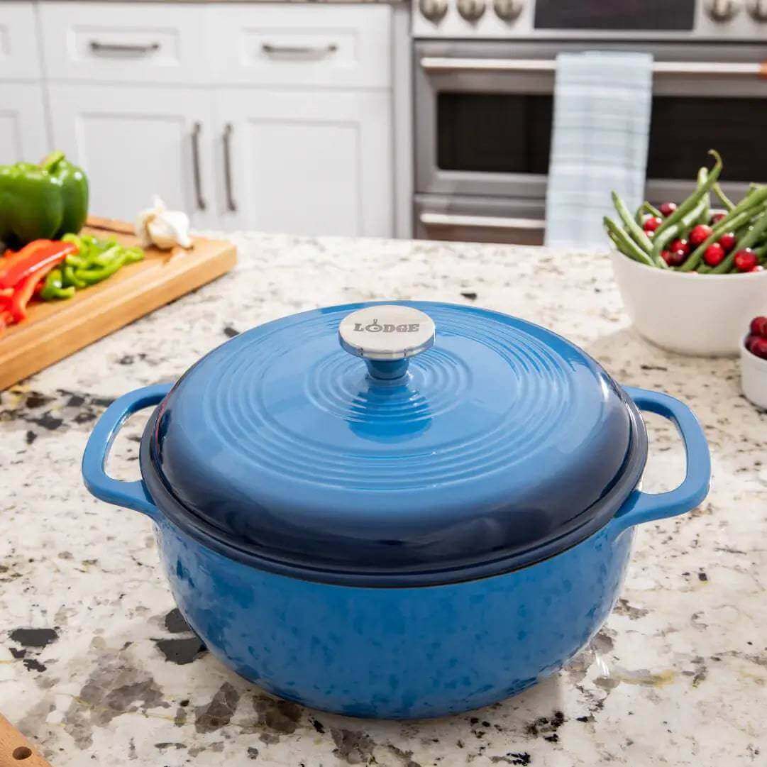 Lodge 6 Quart Enameled Cast Iron Dutch Oven - Blue on kitchen counter, available at Cabin Depot. Perfect for versatile cooking.