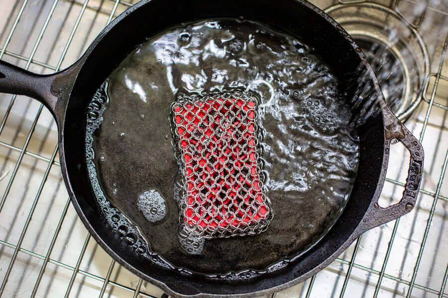 Lodge Chainmail Scrubbing Pad with silicone insert cleaning a cast iron skillet, available at Cabin Depot.