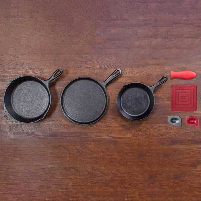 Lodge Skillet Set 6 Piece featuring three cast iron pans and accessories on a wooden surface, seasoned with natural vegetable oil.