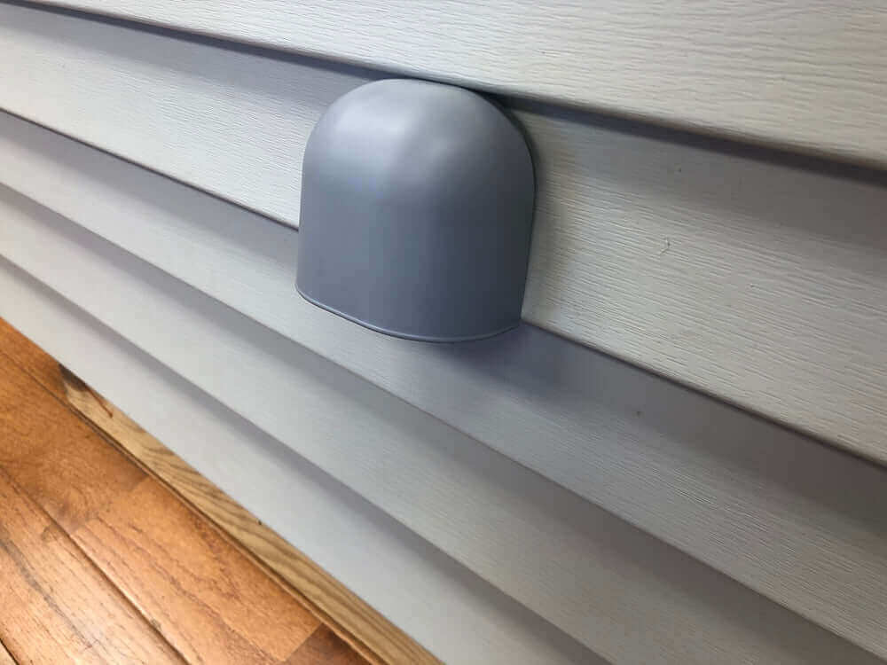 Nature's Head Shell Vent installed on wall, perfect for cabins and homes. Available at Cabin Depot. Weather-resistant and paintable plastic design.