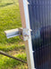 Close-up of solar panel secured with Trifecta Ground Mount Panel Adapter Kit mid bracket, showcasing rail attachment.