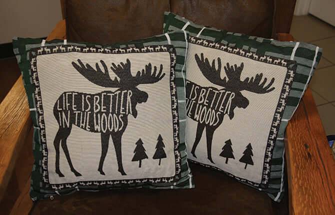 Moose-themed pillows with text 'Life is Better in the Woods', perfect for cabin decor, available at Cabin Depot.