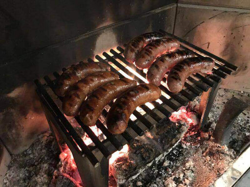 Stainless steel cooking grate with sausages grilling over an open fire, showcasing heavy-duty design for epicurean outdoor cooking.