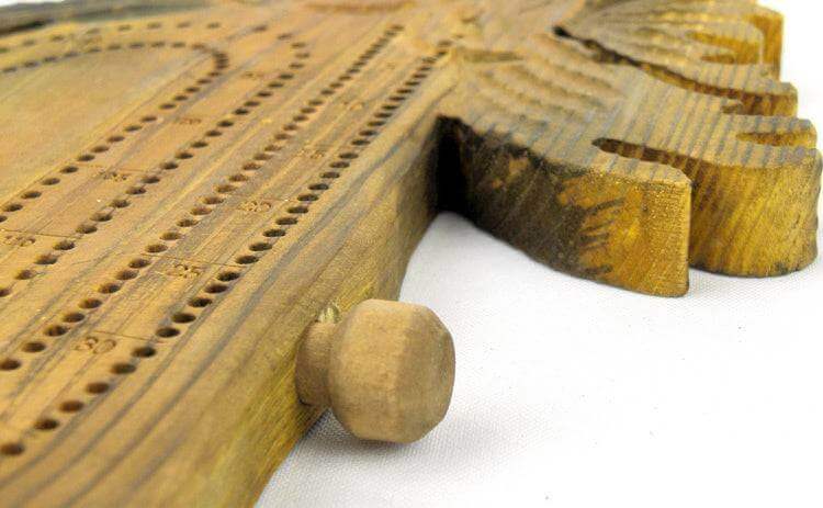 Close-up of NWL hand-carved moose cribbage board from Cabin Depot with peg holder, showcasing detailed craftsmanship and rustic design.