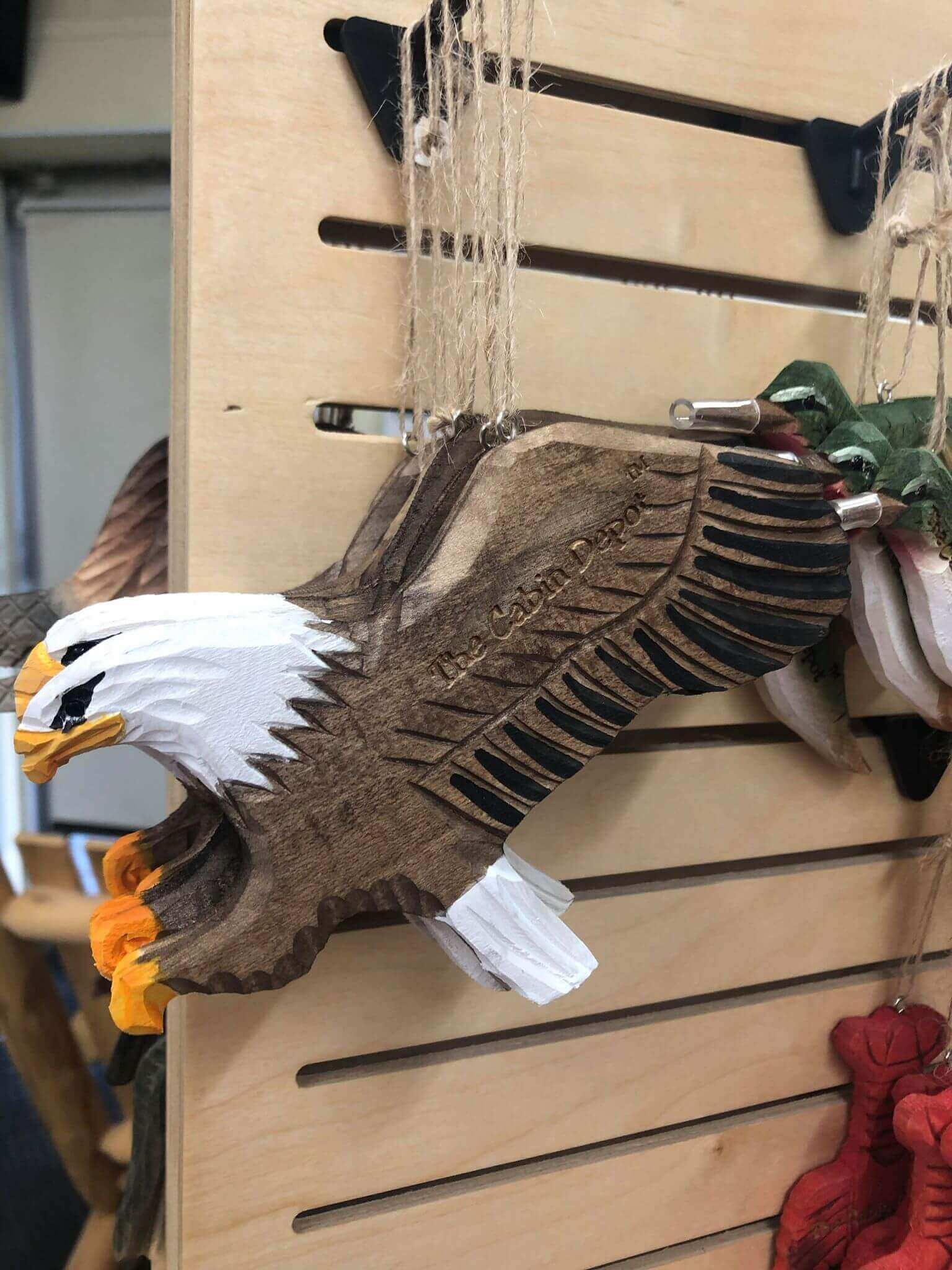 Handcrafted eagle-shaped wooden ornament displayed at The Cabin Depot, showcasing intricate carving and unique design.