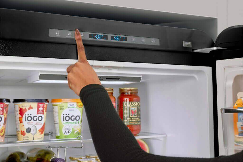 User adjusting temperature on Classic Retro Bottom Mount Refrigerator, 18 cu. ft., ideal for Cabin Depot customers.