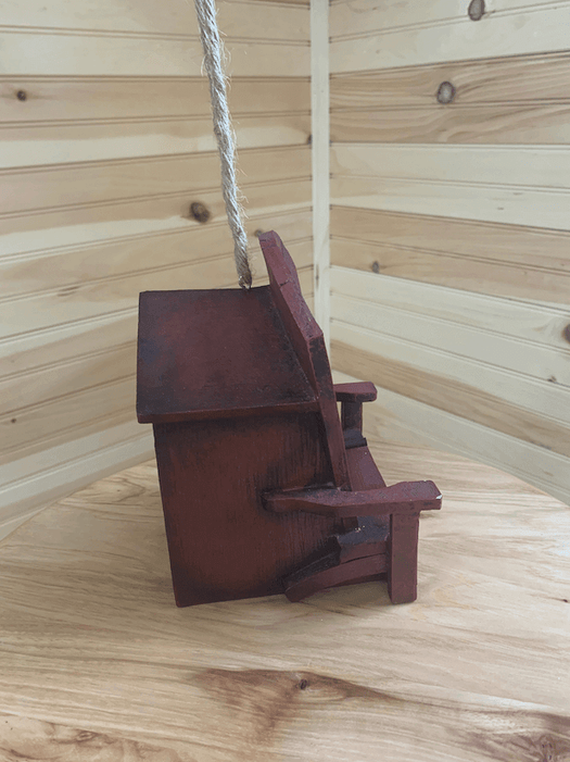 Rustic Adirondack chair birdhouse with a rope hanger, perfect for attracting birds to your cabin or cottage.