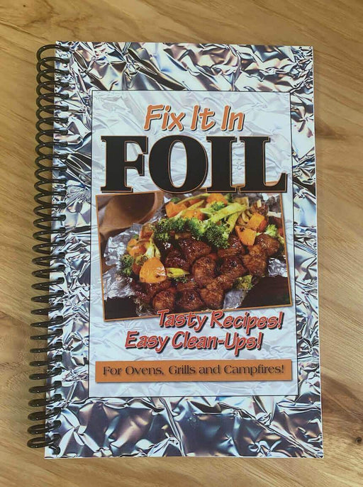 "Fix It In Foil Cookbook cover featuring delicious foil-wrapped meals for ovens, grills, and campfires on a wooden surface"