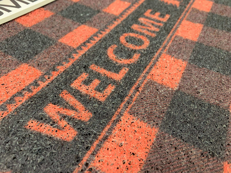 Buffalo plaid welcome floor mat with red and black checkered design, featuring the word "WELCOME" in bold letters.