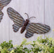 Galvanized butterfly hanger on wooden wall with greenery, perfect for adding an organic touch to home or garden decor.