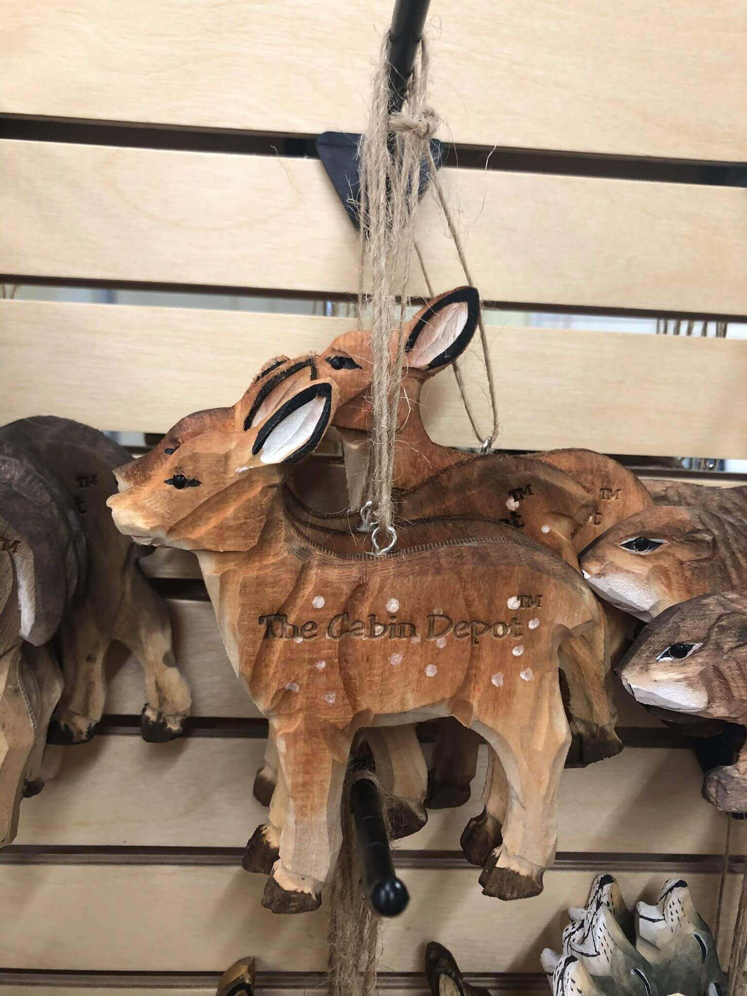 Handcrafted NWL Wooden Ornament with deer design, sold by The Cabin Depot, hanging on a display for rustic decor.