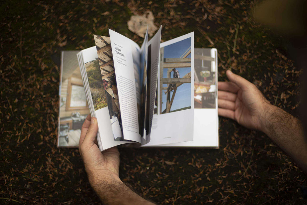 Person flipping through pages of the Cabin Porn Inside book, featuring images of tranquil cabins and handmade homes.