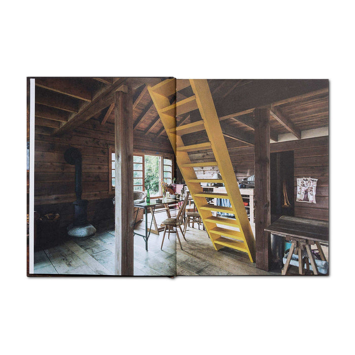 Open Cabin Porn Inside book showing rustic cabin interior with yellow stairs and wooden furniture.