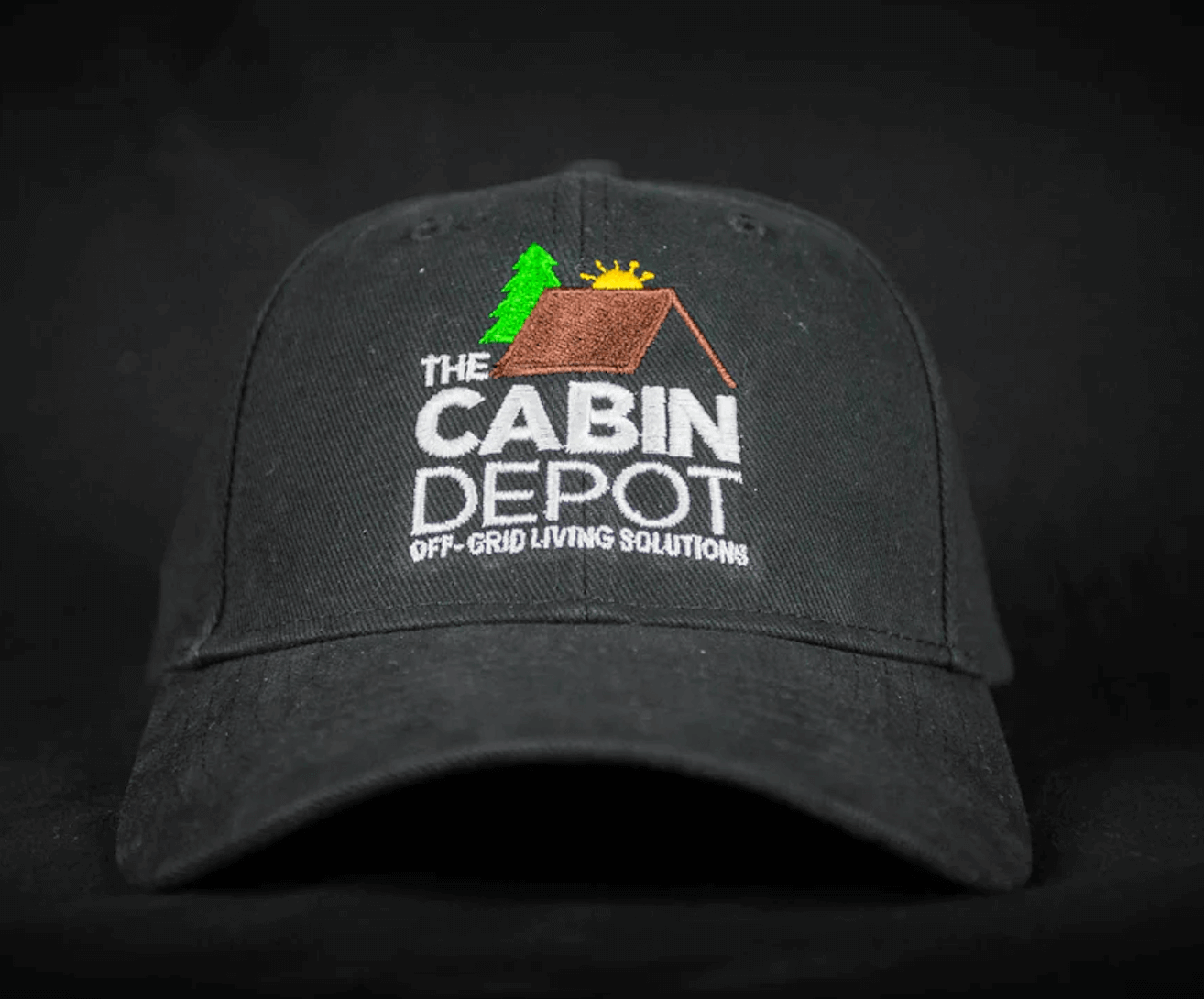 Black baseball cap featuring The Cabin Depot logo, emphasizing off-grid living solutions.