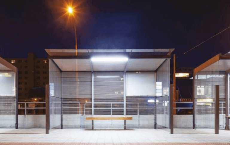 Solar powered LED light kit illuminating a bus shelter at night, suitable for cabins, RVs, workshops. Available at Cabin Depot.