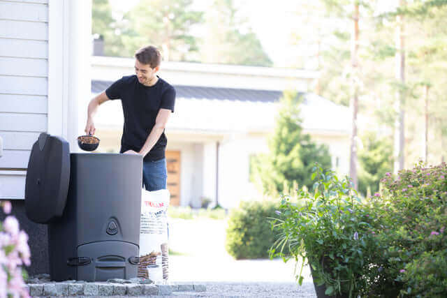 Person using Biolan Biowaste Composter in garden for eco-friendly composting of household waste.